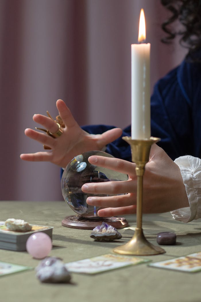 A mystical fortune telling setup featuring a crystal ball, candle, and tarot cards, evoking a mysterious occult vibe.